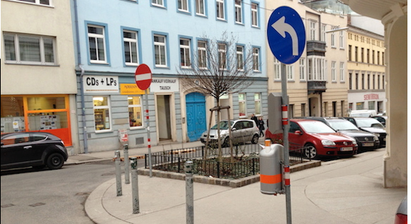 Eine T-Kreuzung: Im Vordergrund das Gebotsschild „links abbiegen“, im Hintergrund rechts das Schild „Einfahrt verboten“.