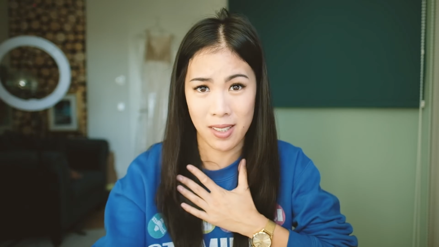 Screesnhot/Nahe Einstellung: Eine junge Frau mit asiatischen Gesichtszügen, blauem Pullover blickt direkt in die Kamera.